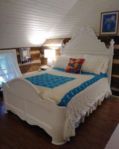 white bed frame with crocheted coverlet