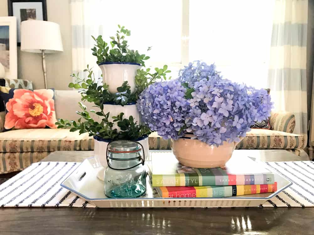 Life Full and Frugal / Summer Living Room Makeover / diy coffee table with vintage tray, blue vintage jar, stacked pottery with greenery and blue hydrangeas arranged in an antique crock pitcher