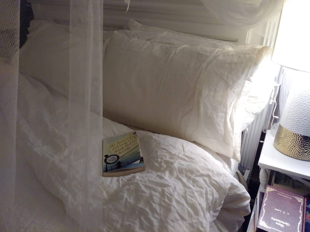 reading a book in a cozy bed with linen sheets life full and frugal