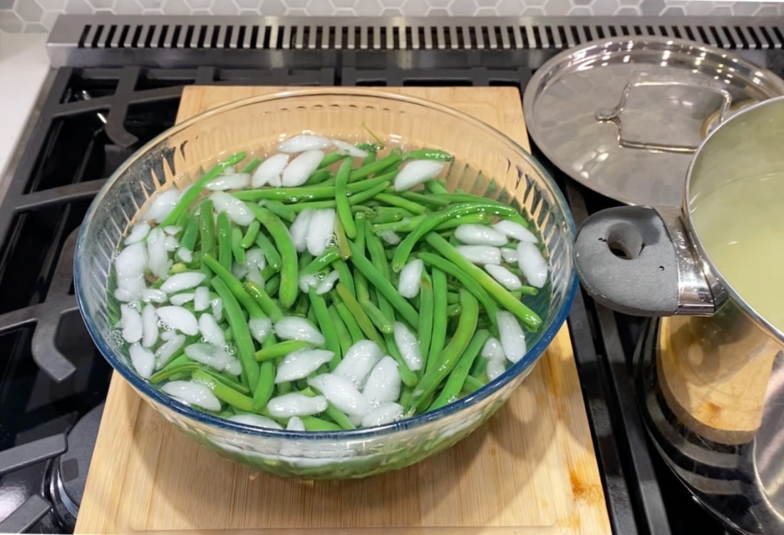 blanched green beans in a large mixing bowl filled with ice water - Life Full and Frugal