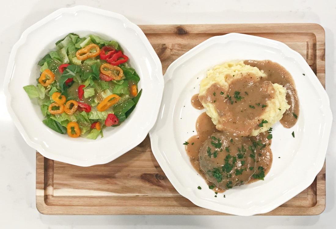 hamburger steaks with mashed potatoes and gravy served with a green salad with red and orange bell peppers  - Life Full and Frugal