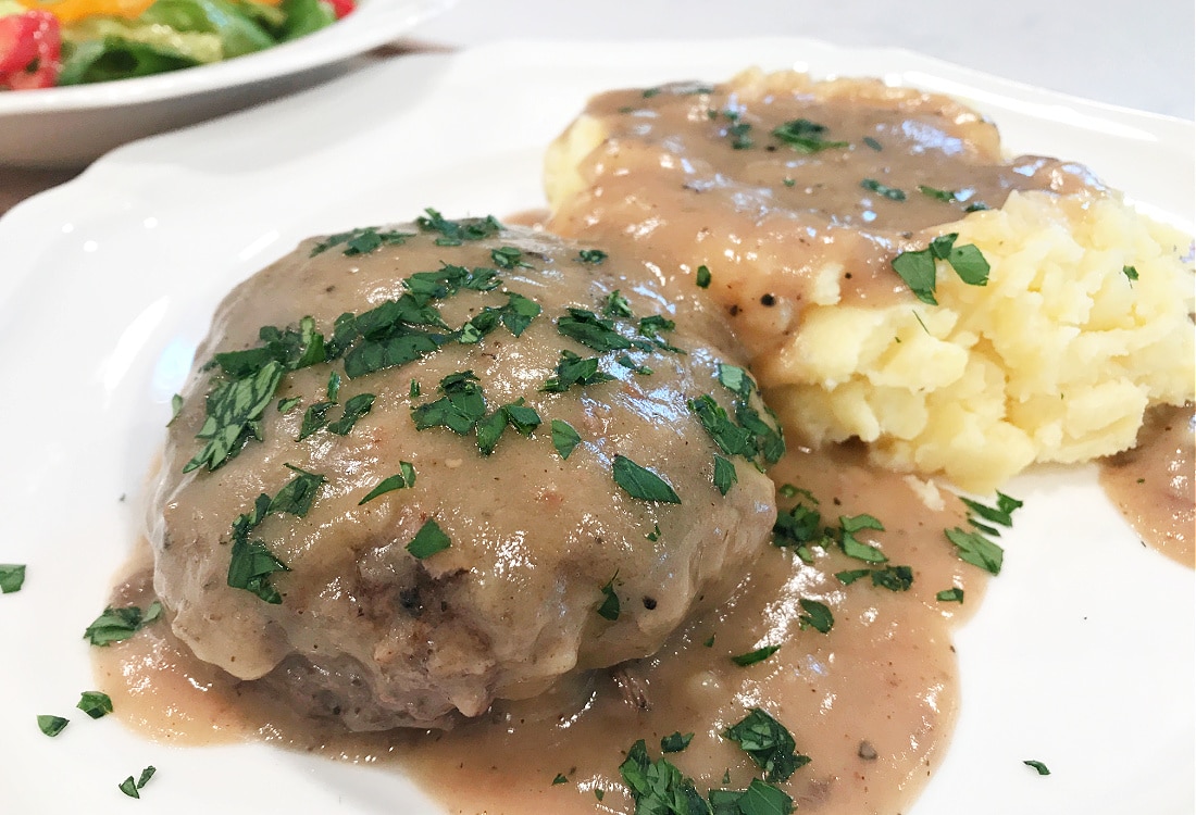 hamburger steaks with mashed potatoes and gravy garnished with chopped fresh parsley - Life Full and Frugal