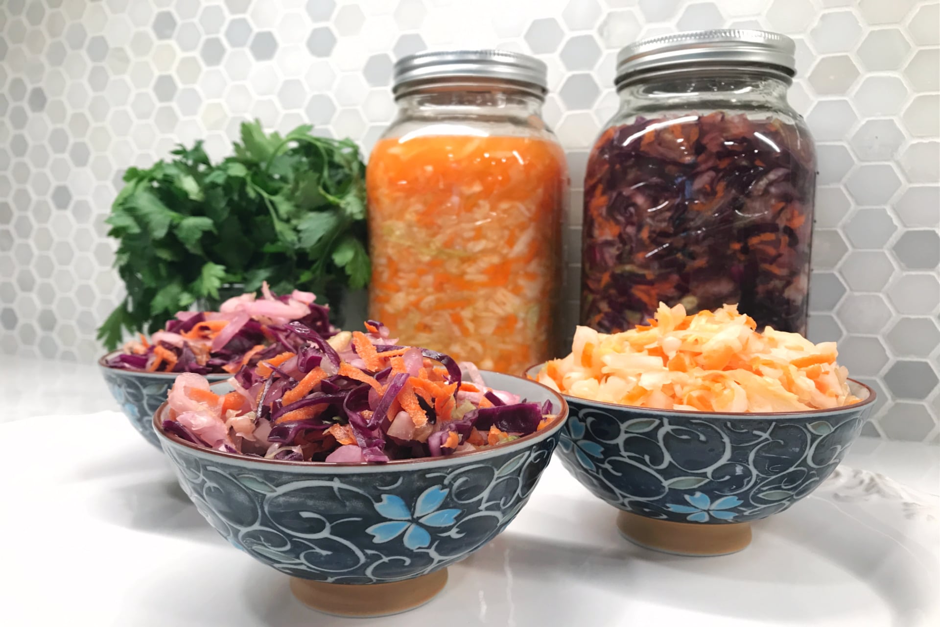 Simple Lacto-Fermented Sauerkraut - Life Full and Frugal - blue floral bowls with red and green sauerkraut in front of two jars filled with sauerkraut