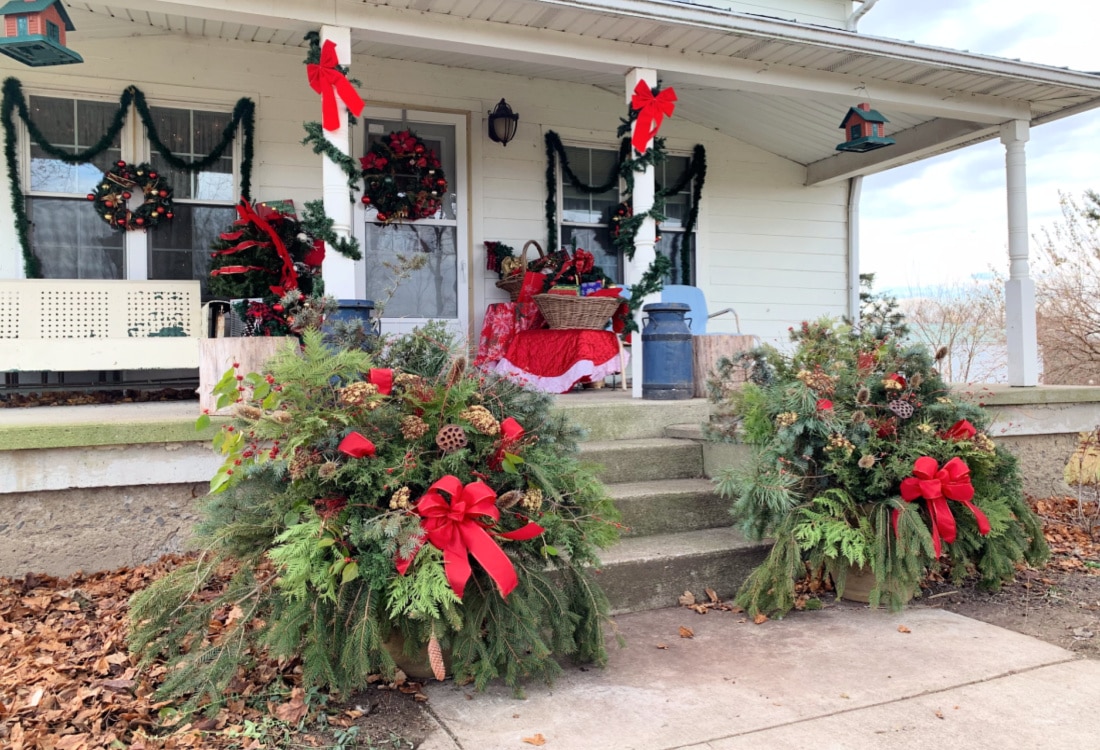 a christmas decorated front porch with evergreen pots life full and frugal