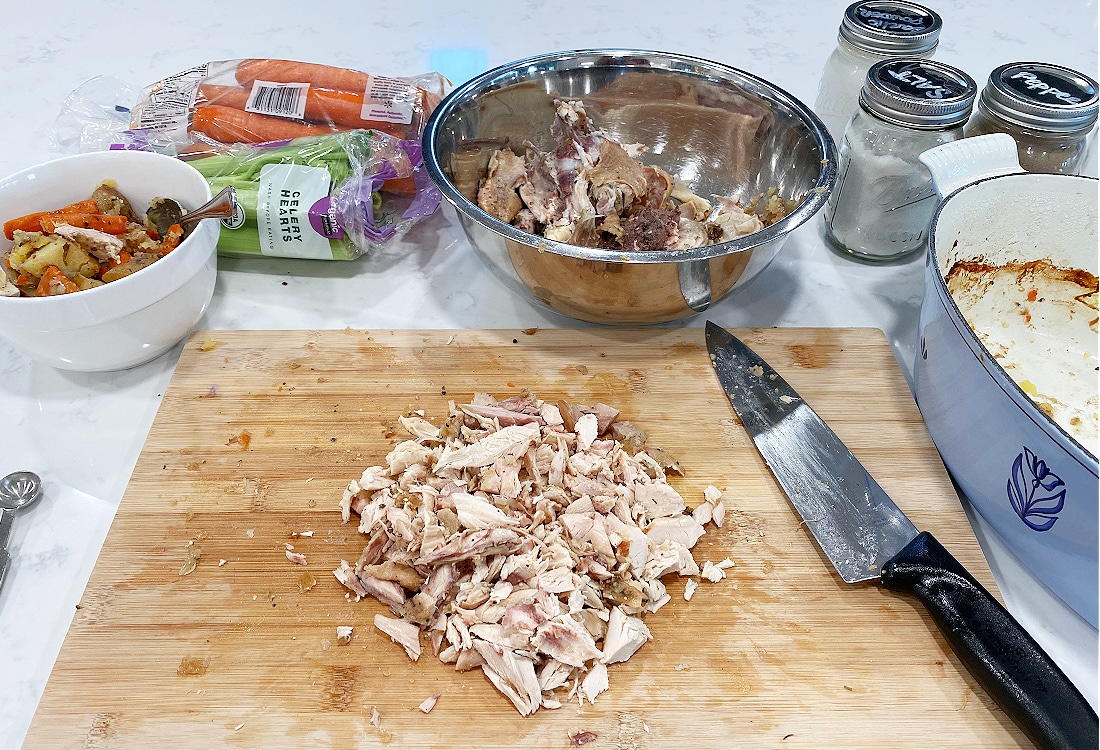 leftover chicken cut up on a bamboo cutting board surrounded by veggies for a chicken biscuit pot pie recipe -Dutch Oven Chicken Biscuit Pot Pie - Life Full and Frugal
