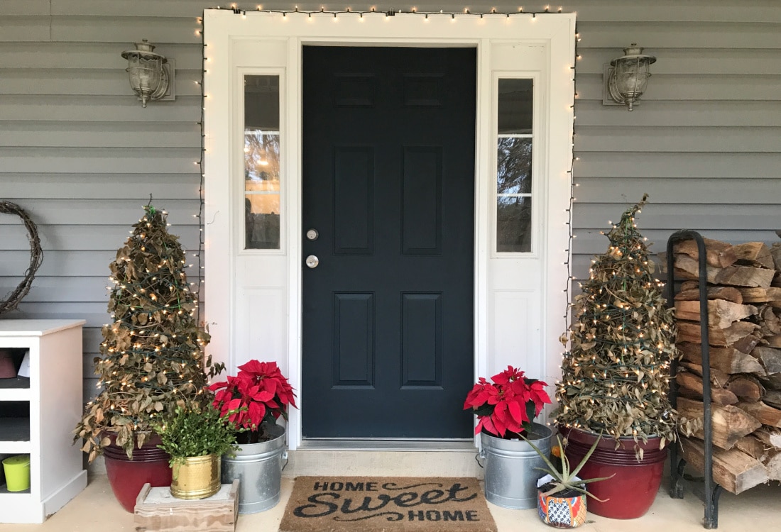 front porch with blue door and white trim decorated with tomato cage Christmas trees and red poinsettias -Tomato Cage Christmas Trees - Life Full and Frugal