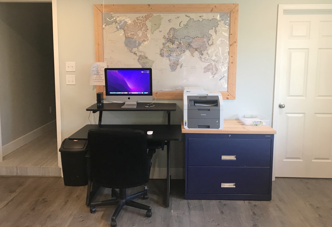 homeschool classroom desk placed under world map on the wall with a blue filing cabinet to the right -Homeschool Classroom Overhaul and Tour - Life Full and Frugal